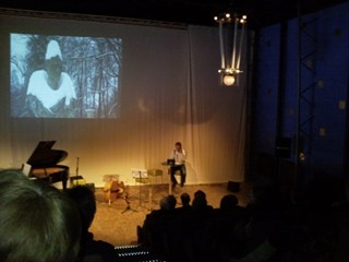 Een blik van uit de zaal. Op het podium kunstenaar Jan Doms.