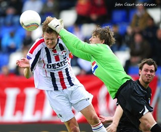 foto: Ruud Swinkels stompt de bal voor het hoofd van zijn broer Arjan weg