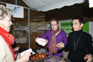 Marie-Anne Koning koopt oliebollen bij Carina Verbunt en dochter Inge (m)