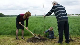 Wethouder Moorman plant een boom met Jan van Eijck en kleinzoon Rick